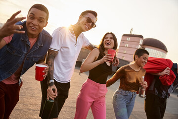 Young friends enjoy a lively rooftop party as the sun sets, creating joyful memories together