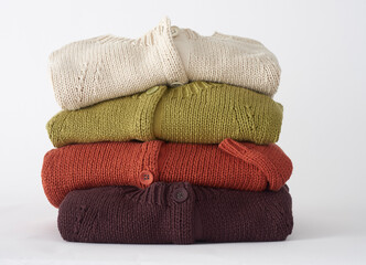 Stack of colorful knitted cardigans fashionable wool clothing on white background