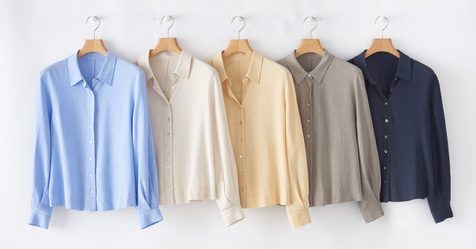 Collection of pastel colored linen shirts hanging on a white wall