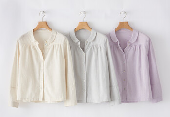 Pastel cotton blouses hanging on wooden hangers apparel photography