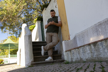 Adult man leaning on wall using smartphone