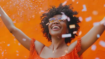 A cheerful woman smiling and holding up her hand filled with confetti.