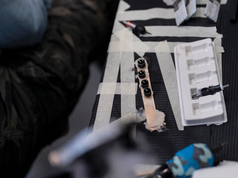 Overhead view of tattoo ink caps arranged on striped tray with supplies in background
