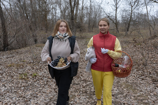 Two young friends heading to a cozy autumn picnic with wicker basket, blanket and fresh fruit