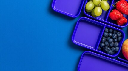 Brightly colored fruits are neatly placed in purple containers on a bold blue background. The scene showcases grapes, strawberries, blueberries, and an apple, promoting healthy eating