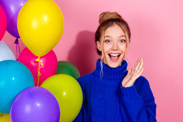 Happy young woman with colorful balloons in a pink studio celebration full of joy and vibrant energy