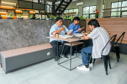 Diverse Colleagues Collaborating On Project Using Digital Devices In Modern Co Working Cafe - Powered by Adobe