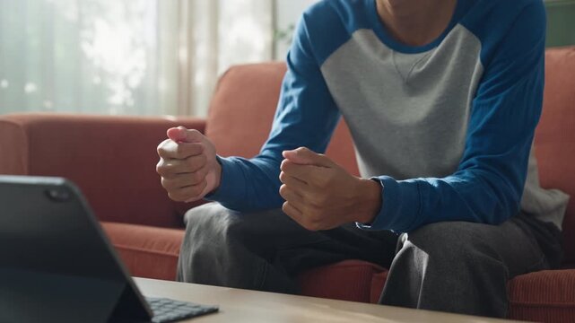 Close-up.Asian teenage man learning sign language via internet with technology on tablet at home