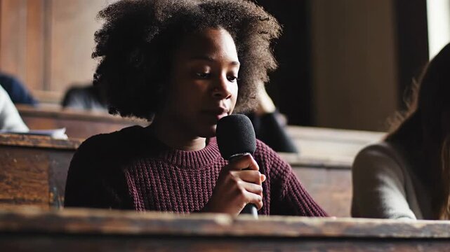 Young person speaking into microphone at educational event or public discussion forum