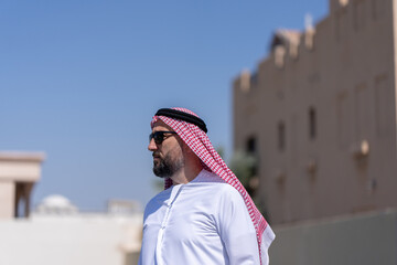 Man wearing traditional arab clothing walking outside in the city. Beautiful sunny weather. High quality photo