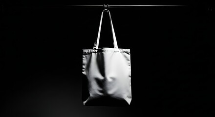 Minimalist white tote bag hanging against a dark background