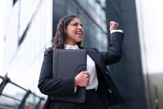 Businesswoman celebrating success in urban setting during daytime