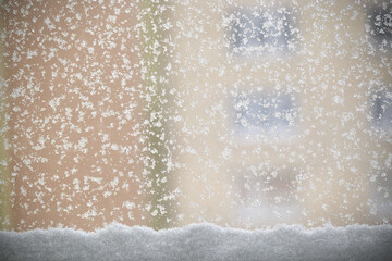 Snowflakes on a window with a blurred building in the background