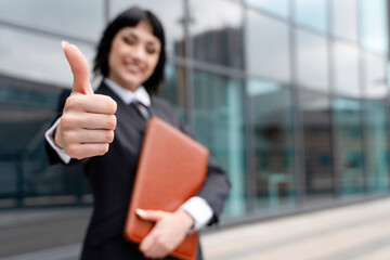 Businesswoman celebrating success while holding a portfolio outside a modern office building in the city