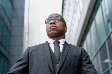 Confident man in business suit stands in urban setting with modern architecture in the background