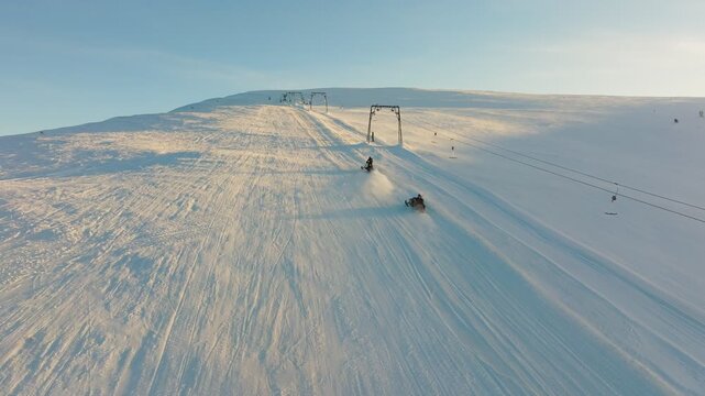 Bright snowy hillside, Golden glow over groomed slopes, Dawn illuminates snowy peak with active skiers, Sunshine highlights icy ridge and bustling winter recreation scene