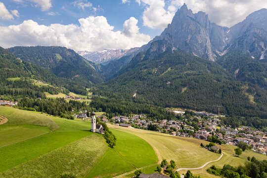 St. Valentin church surrounded by meadows and fields, with Schlern massif in background, Castelrotto in Dolomites Alps. South Tyrol, Italy
