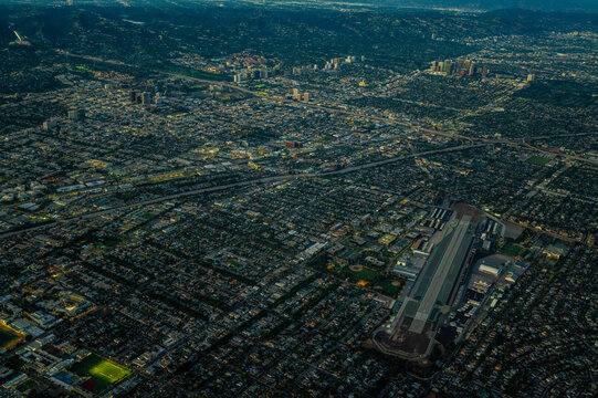 Aerial view of hillside residential neighbourhoods and sports fields in Los Angeles County, California, showing dry mountain terrain and suburban grid patterns on a clear sunny day