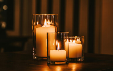 Three lit candles of varying sizes in clear glass holders creating a warm and inviting ambiance