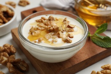 Delicious Greek yogurt with honey and walnuts served on white table, closeup