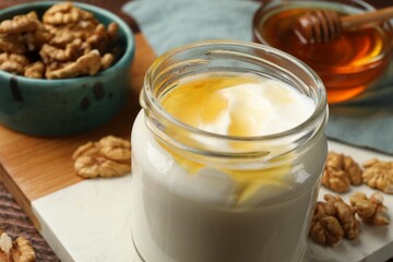 Delicious Greek yogurt with honey and walnuts served on wooden table, closeup