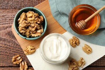 Delicious Greek yogurt with honey and walnuts served on wooden table, flat lay