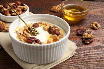 Delicious Greek yogurt with honey and nuts served on wooden table, closeup
