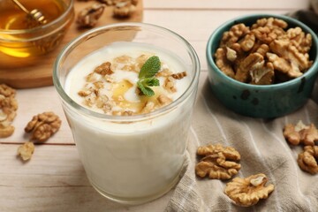 Delicious Greek yogurt with honey and walnuts served on white wooden table, closeup
