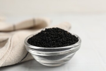 Aromatic black caraway in glass bowl on white table, closeup