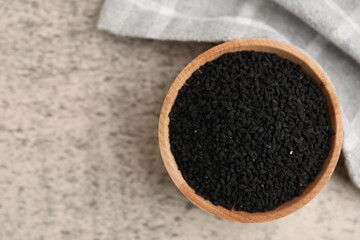 Aromatic black caraway in wooden bowl on grey table, top view. Space for text