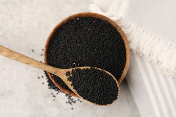Aromatic black caraway in wooden bowl and spoon on light grey table, top view