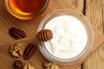 Delicious Greek yogurt with honey and nuts on wooden table, flat lay