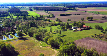 Aerial view of rural agricultural landscape featuring farm buildings, cultivated fields, forests, and aquaculture fish ponds © Frank