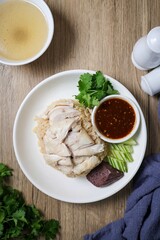 Chicken and rice with coriander and cucumber with sauce and soup in a white plate, hainanese chicken rice, thai called khao man gai, asian food, thai food