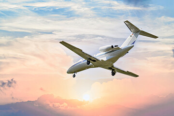 Private business jet flying under the sunset sky