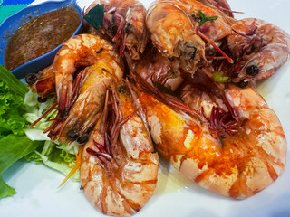 A plate filled with large, cooked prawns arranged closely together, their shells glistening with oil and light seasoning.