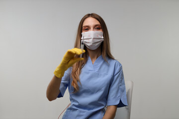 Female healthcare worker in blue scrubs holding a syringe