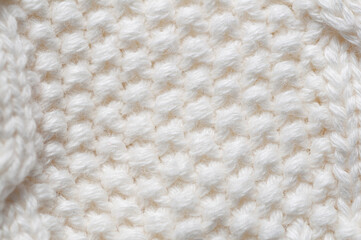 Close-up of a textured white knitted fabric with a repeating pattern