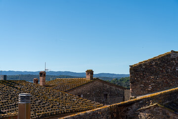 Morning in a boutique hotel with a view on classic medieval buildings tiled roofs and the mountains in small Spanish village in Girona region. Calm getaway destination near Barcelona. 