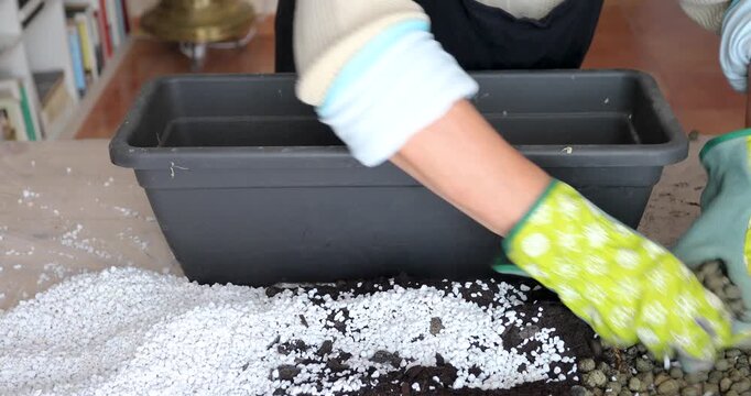 Close-up of gloved gardening hands preparing a substrate by mixing potting soil, perlite and expanded clay. Ideal base for healthy succulents and proper drainage. No audio.