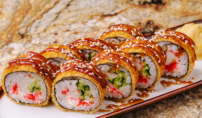 Delicious sushi rolls with spicy sauce and sesame seeds served on a plate