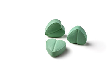 Turquoise heart-shaped cardiology pills isolated on white background.