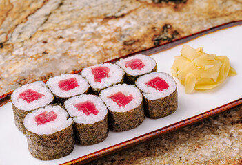 Fresh sushi rolls with tuna and pickled ginger on a wooden platter