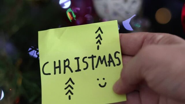 Un primer plano de una nota de color amarillo  con la palabra navidad en un fondo de luces de colores. Fiesta de Diciembre y Fin de a&ntilde;o