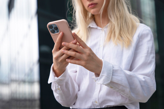 Young woman using smartphone outdoors in urban setting on a sunny day