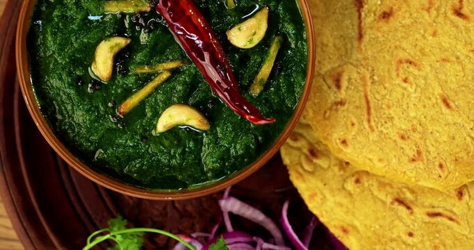 Makki Ki Roti & Sarson Ka Sag is basically Corn floor flat bread & curry using mustard greens respectively. Popular Punjabi food. Served in a bowl and plate over moody background. selective focus