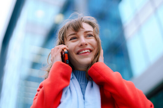 Smile and connection: joyful woman talking on phone in urban setting during sunny day - Powered by Adobe