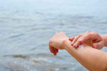 Hand of female holding sunscreen. Very sun light Sky background.Health concepts and skin care	