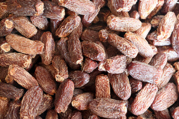 Dried dates close up showing dense pile with wrinkled skins and natural colors