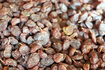 Fresh dried raisins close up filling frame with glossy, brown, and reddish tones